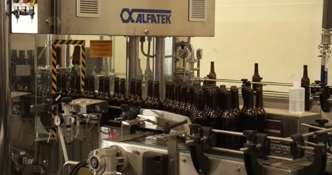 Beer bottles enter bottling machine and exit sealed in Berlin brewery Stock Footage 335143575