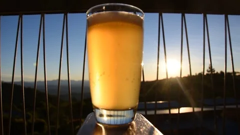 Beer bubbling uplcoase out of focus with sunset and mountains Stock Footage 77491787