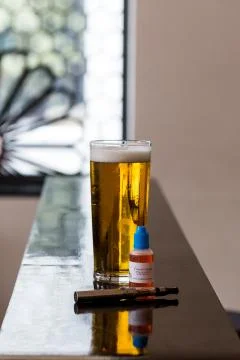 Beer, e-juice and electronic cigarette on table Stock Photos