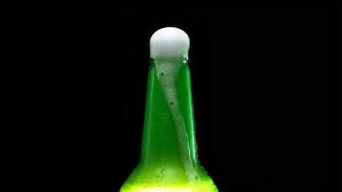 Beer foam flows down a bottle. Foam flows down a bottle of lager beer. Video stock 155354761