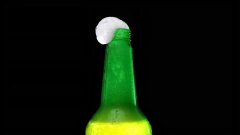 Beer foam flows down a bottle. Foam flows down a bottle of lager beer. Video stock 155436242