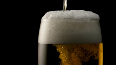 Beer foam flows down the glass of beer. Close up. Black background. Stock Footage 135124168