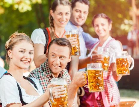 In Beer garden - friends drinking beer in Bavaria on Oktoberfest Stock Photos