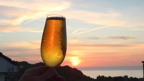 Beer glass being held in front of Sunset in Devon, UK Stock Footage 242074572