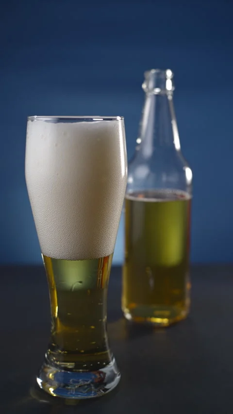 Beer is in a glass. It is on the table. Bubbles are in the beer. Stock Footage 295773000