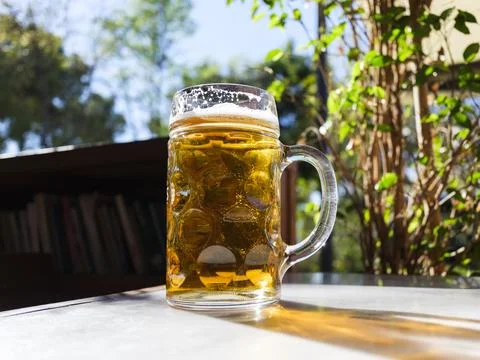 Beer glass on table with sunlight reflections in bar Foto stock