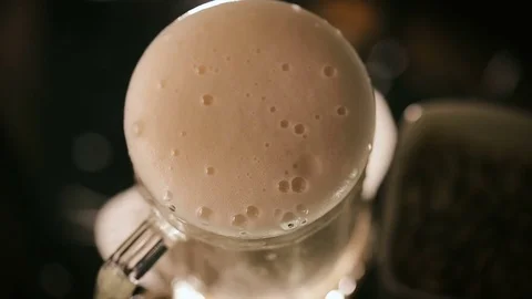 Beer Over the Edge. Full mug amber beer on a black background Video stock 75660050