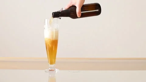 Beer is poured from dark brown bottle into beer glass. Stock Footage 263204455