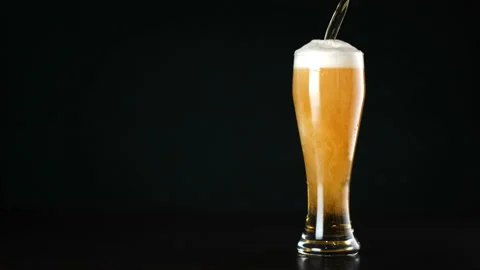 Beer is poured into a glass on black background Stock Footage 143390976