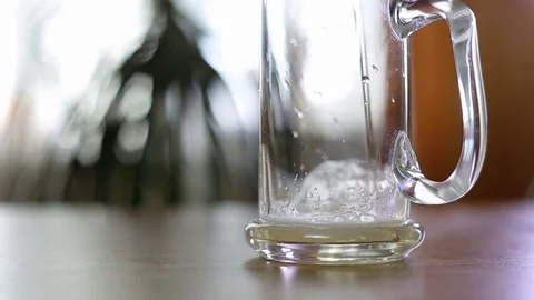Beer is poured to half empty mug on table Stock Footage 77570994