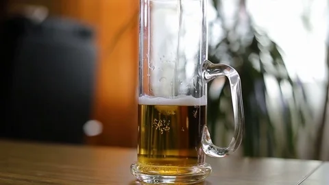 Beer is poured to half empty mug on table Stock Footage 77571016