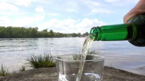 Beer is poured in slow motion on the river bank. Stock Footage 197266862