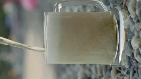 Beer is pouring from a bottle in slow motion into a glass on the sand Stock Footage 143953553