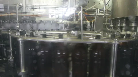 Beer is pouring into rotating plastic bottles from a factory machine Stock Footage 116972637