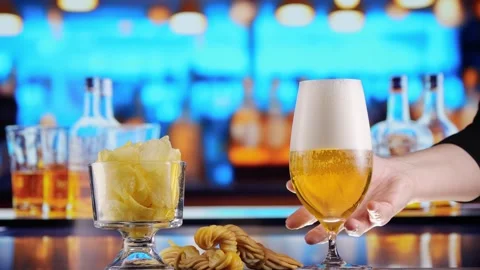 Beer pours into a glass, forming bubbles and a frothy head. Snacks and Chips in Stock Footage 279484853