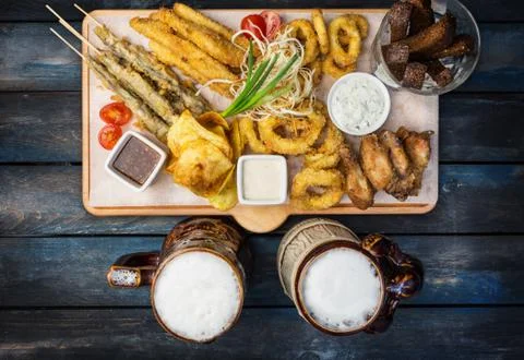 Beer snacks set. Fish set served on cutting board with the mugs, on the wooden Stock Photos