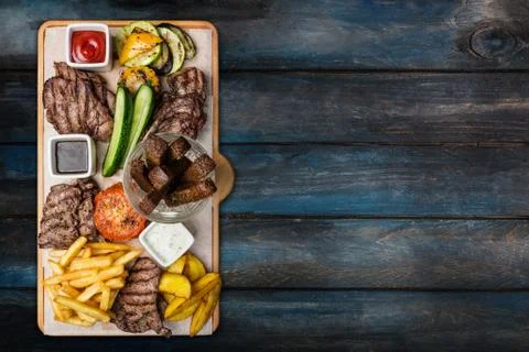 Beer snacks set. Meat set served on cutting board with the wooden background. Stock Photos