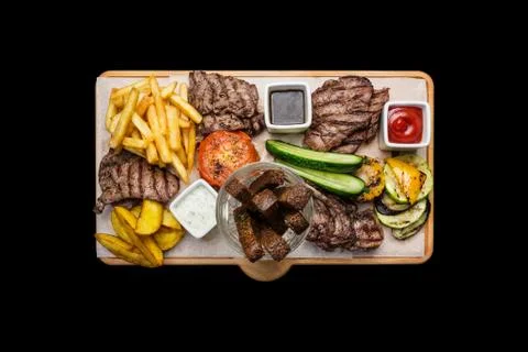 Beer snacks set. Meat set served on cutting board, isolated on the black Stock Photos