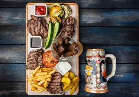 Beer snacks set. Meat set served on cutting board with the antique mug, on the Stock Photos
