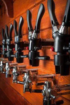 Beer taps for draught drinks are built into wooden boards. Stock Photos