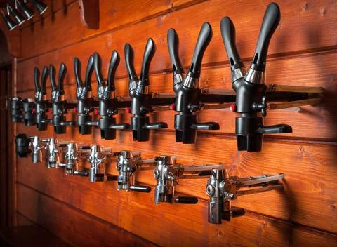 Beer taps for draught drinks are built into wooden boards. Stock Photos