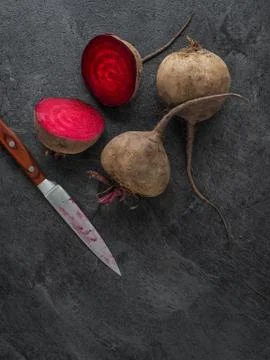 Beetroot cut in half and knife on dark table. Overhead shot. Stock Photos