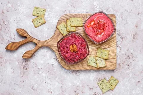 Beetroot hummus on cutting board with salty cookies on light background Stock Photos