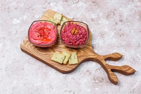 Beetroot hummus on cutting board with salty cookies on light background Stock Photos