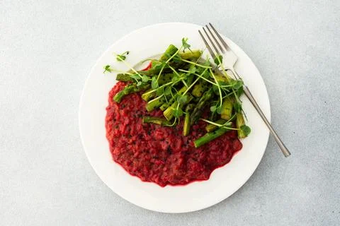 Beetroot risotto with rice and sesame seeds, baked asparagus with microgreens Foto stock