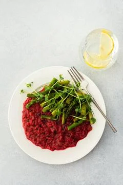 Beetroot risotto with rice and sesame seeds, baked asparagus with microgreens Stock Photos