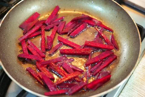 Beetroot slices in a frying pan. large pieces of beets are fried in a pan. .. Stock Photos
