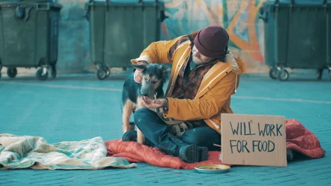 A beggar is feeding his dog while sitting on the ground Vidéo 168128631