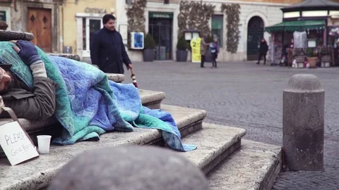 Beggar sleeping on stairs in the city while a man wake him leaving alms Stock Footage 74714521