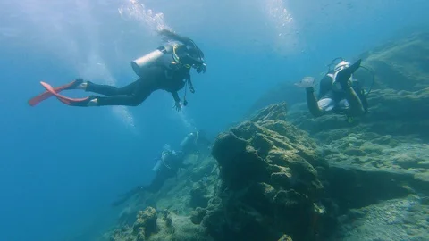 Beginner PADI diver descends to join a group of other divers Stock Footage 128768176