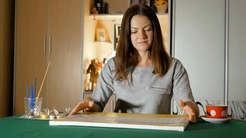 Beginner painter takes her picture in her hands and examines it with smile Stock Footage 83735654