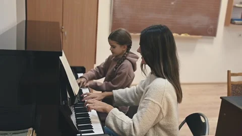 A beginner pianist practices under a teachers supervision, mastering basic Stock Footage 305650626