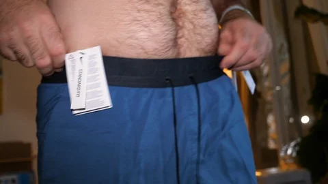 Beginner runner chubby man with big belly measuring shorts Stock Footage 111536180