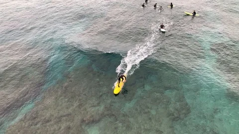 Beginner surfers learning to surf over coral reef shot from drone Video stock 124890543