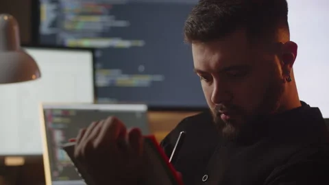 A beginner web programmer sits in his room in front of several monitors and Stock Footage 236644305