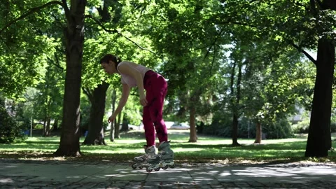 Beginner woman learning inline skating in a park Stock Footage 341477321