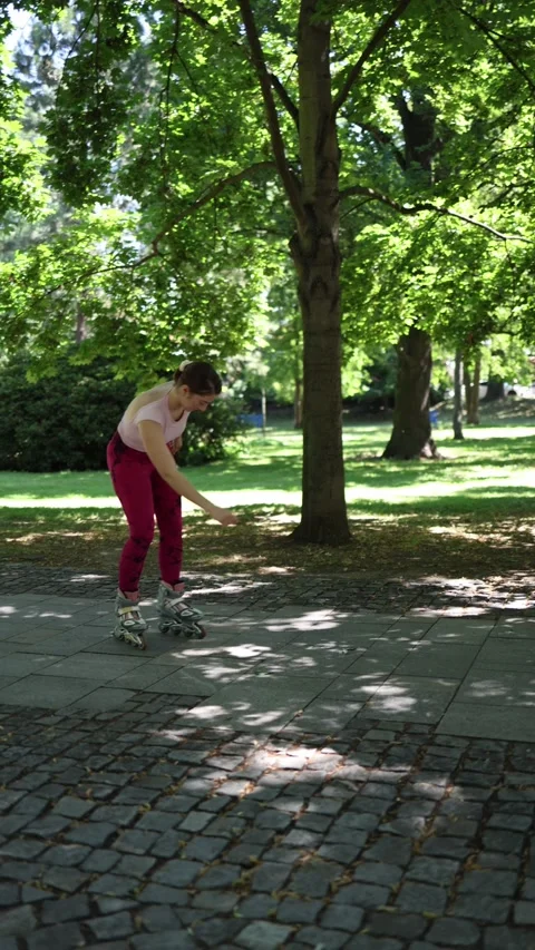 Beginner woman loses balance while learning to roller skate in a park Stock Footage 341476509