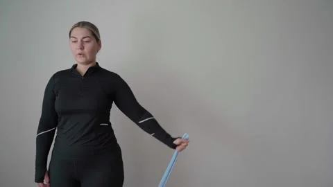 Beginner Woman Performing Side Shoulder Raise With Resistance Band at Home Stock Footage 340545205