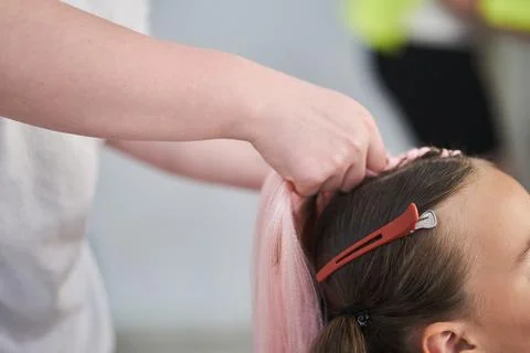 The beginning of braiding braids using pink kanekalon material. The hands of the Fotos de archivo