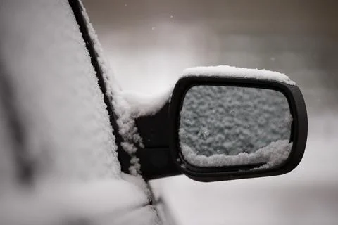 The beginning of spring. Unexpected snow covered cars and roads. Door mirror  Stock Photos