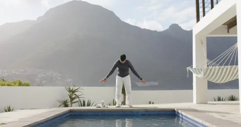 Beginning warm-up, Indian man stretching on pool deck, rotating wrists, folding Stock Footage 336844561