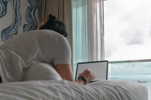 Behind angle of man work on the bed with sea view. Concept of workation. Photos