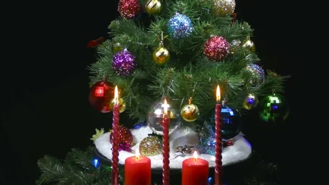 Behind burning candles closeup rotates a decorated green Christmas tree Stock Footage 166683996