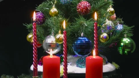 Behind burning candles a large decorated Christmas tree revolves Stock Footage 166683683