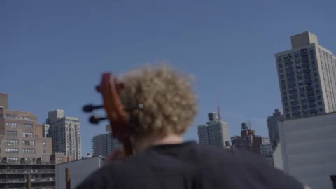 From behind cellist playing on Brooklyn rooftop Video stock 111044397