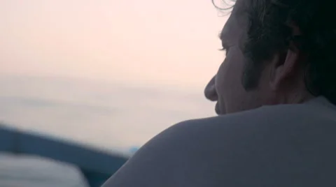 From behind close up of man looking around on a small boat during sunrise Video stock 57103028